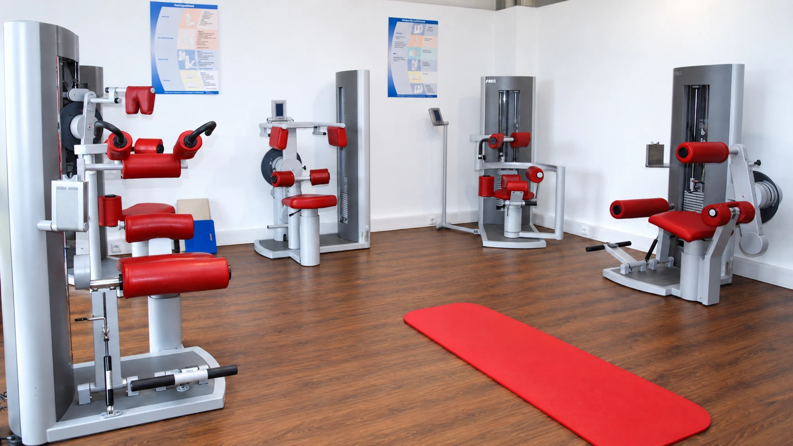 Gerätetraining im Fitnessstudio in Ansbach-Claffheim: silberne Kraftgeräte mit roten Polstern und rote Trainingsmatte auf Holzboden