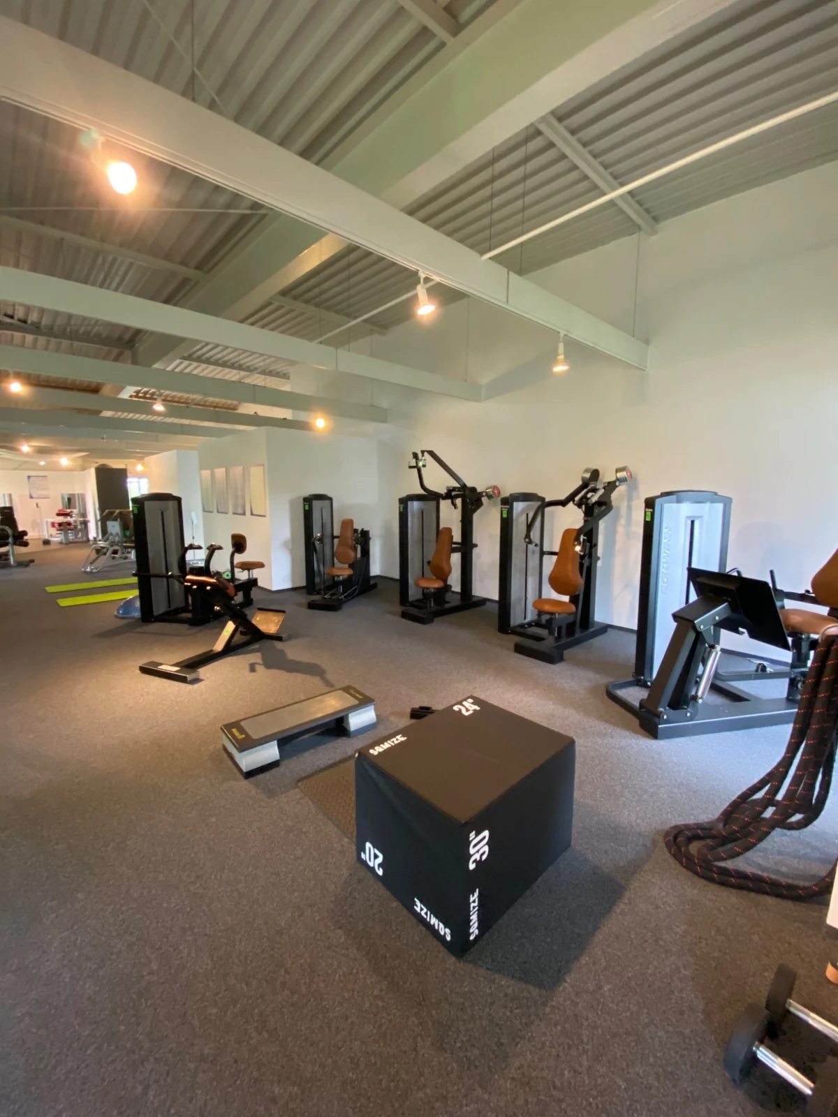 Kraftgeräte und freie Trainingsfläche mit Step, Trainingsbox und Seilen im Fitnessstudio