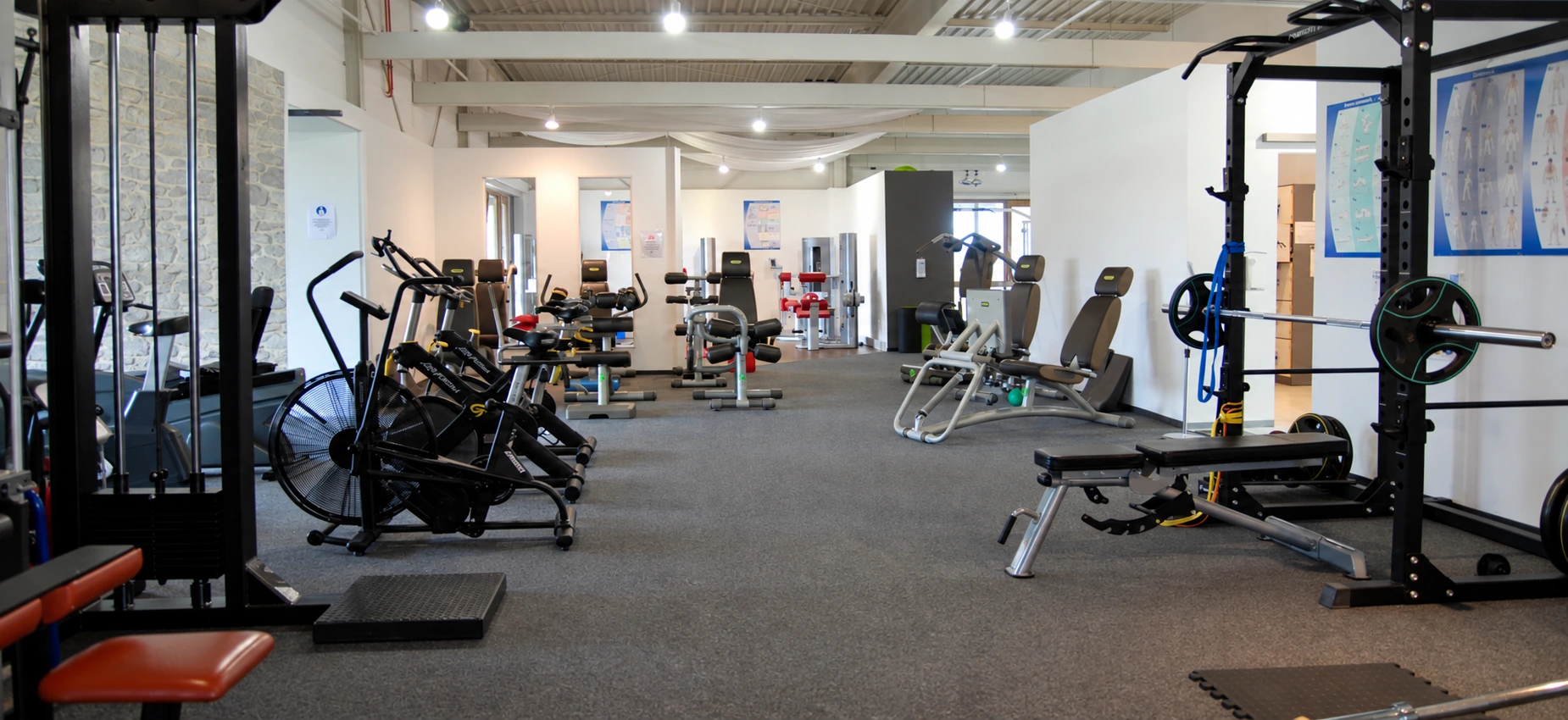 Großer Fitnessbereich mit unterschiedlichen Trainingsgeräten und großzügigen Abständen